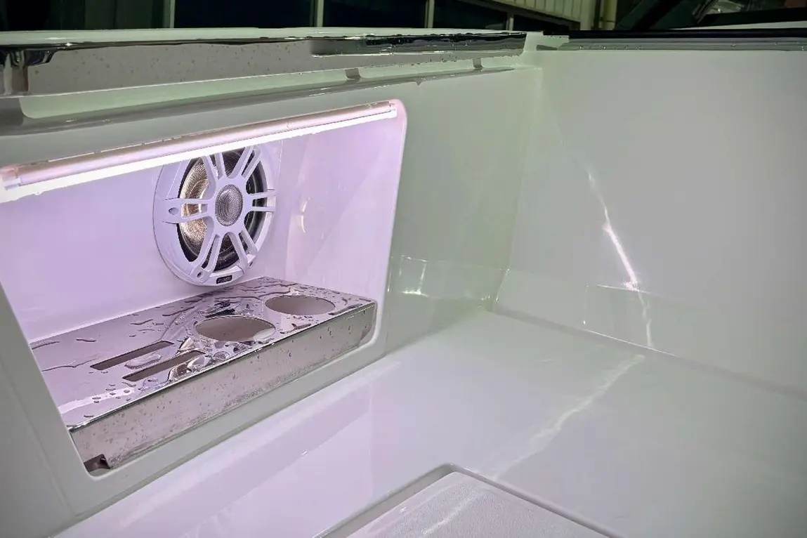 Interior view of a marine console featuring a speaker, illuminated shelf, and stainless steel cup holders with water droplets.